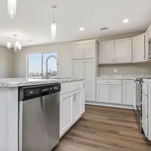a kitchen with white cabinets and a stainless steel dishwasher