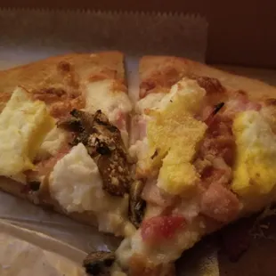 Breakfast pizza with egg, bacon, ham and mushrooms over a handmade pesto.