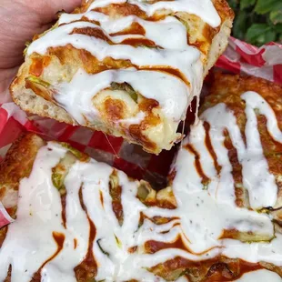 a hand holding a piece of pizza