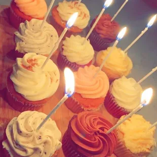 a number of cupcakes with lit candles