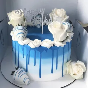 a blue drip cake with white roses
