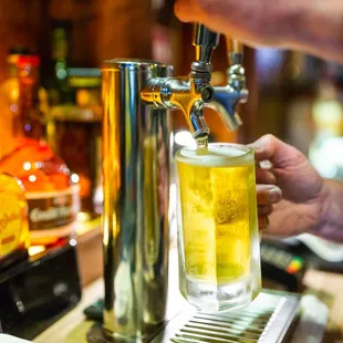 a person pouring a beer from a tap