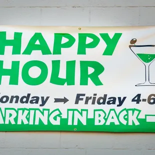 a happy hour sign on a brick wall