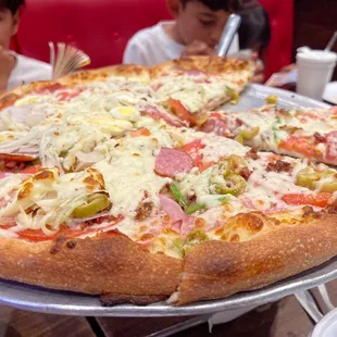 two children sitting at a table with a pizza