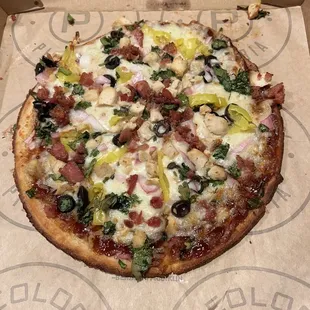 custom GF Cauliflower Pizza with BBQ sauce, black olives, banana peppers, red onion, cilantro, chicken and bacon.