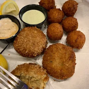a plate of crab cakes and dipping sauces