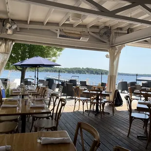 tables and chairs on a deck overlooking the water