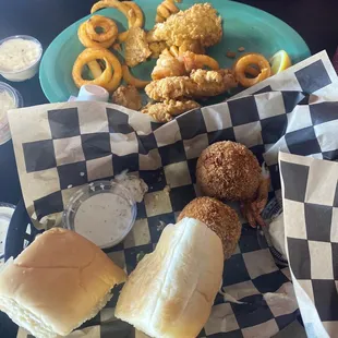 Half finished boudin ball appetizer and fried fish / oyster basket with curly fries.