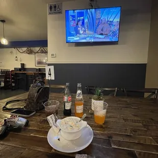 a wooden table with a bowl of soup and a bottle of orange juice