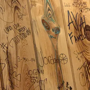 Woody the alien face along with some of the copious names and tags that are all over the walls.