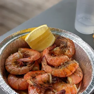 a bowl of cooked shrimp with lemon wedge