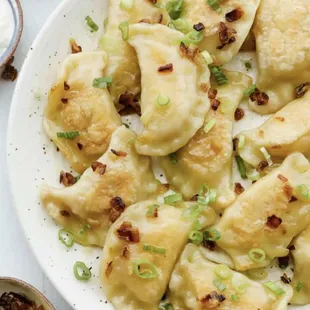 a plate of pierogi with scallions