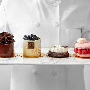 a chef holding a tray of desserts