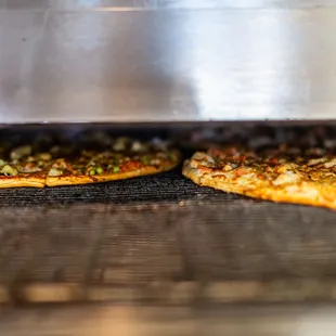 two pizzas cooking in an oven