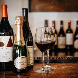 three bottles of wine and a glass of wine