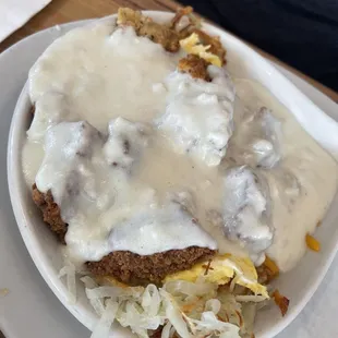 Chicken fried steak with hash browns and eggs underneath