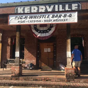 ows a man walking his dog in front of a brick building