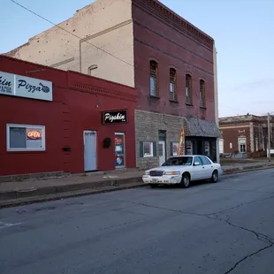 a white car parked in front of a brick building