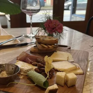 a cheese board with cheese, crackers, and a glass of wine