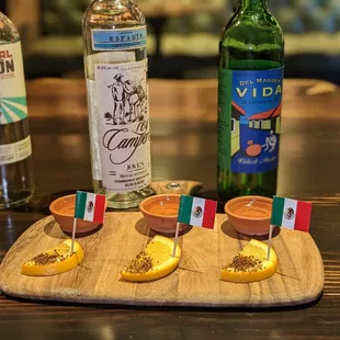 a wooden board with a bottle of liquor and a plate of orange slices
