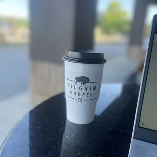 a cup of coffee on a table next to a laptop