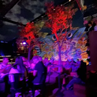 people sitting at tables under a tree