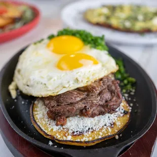 a steak sandwich with an egg on top