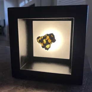 Meteorite sliver floated by magnet in lighted shadowbox