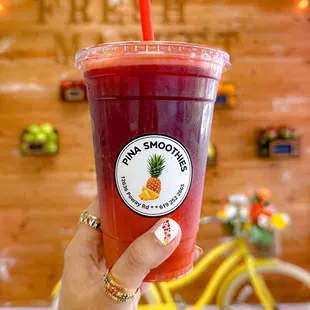 a hand holding a cup of fruit smoothie