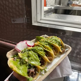 a person holding a tray of tacos