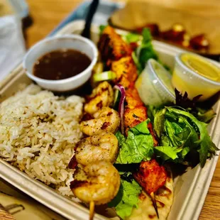 Shrimp Kebab platter with black beans, white rice, salad, pita bread, and a side order of chicken kebab.