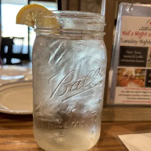 a mason jar filled with ice and a slice of lemon