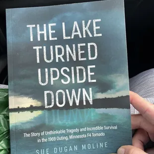 a person holding a book about the lake turned upside down