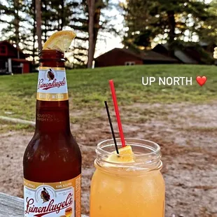 a beer and a drink on a picnic table