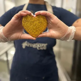 a woman holding a heart shaped pastry