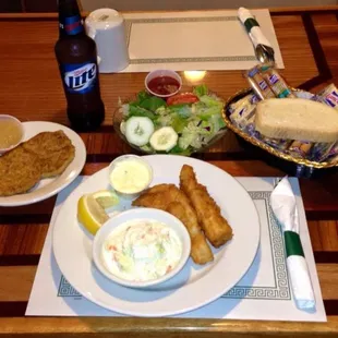 a plate of fried fish, a bowl of coleslaw, a bowl of coleslaw, and a salad