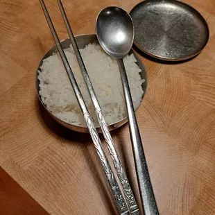 Banchan comes with a bowl of white rice. Metal chopsticks. Long handled spoon.