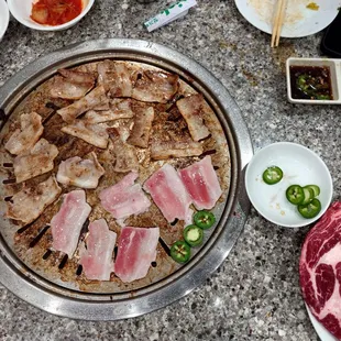 Pork belly on the grill, ribeye waiting for grill space.