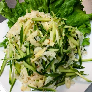 a plate of salad with lettuce and cucumbers