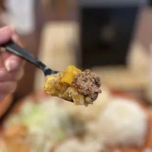 a hand holding a fork full of food