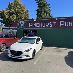 a white car parked in front of the pub