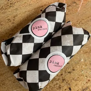 two sandwiches wrapped in black and white checkered paper