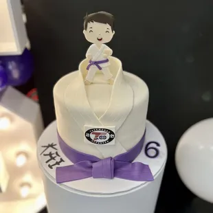 a white cake with a purple ribbon