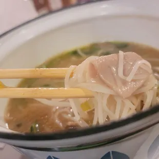 a bowl of soup with chopsticks