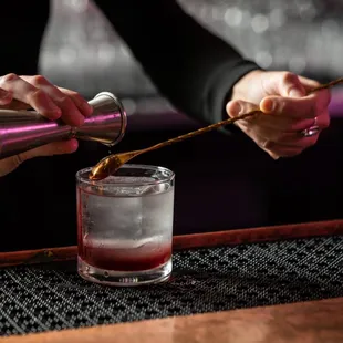 a bartender pouring a drink into a glass