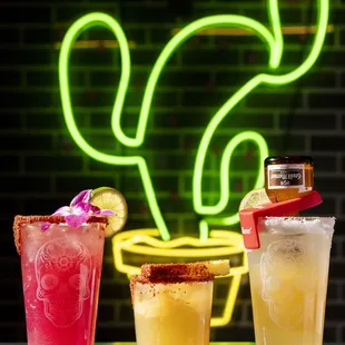 three different cocktails on a bar