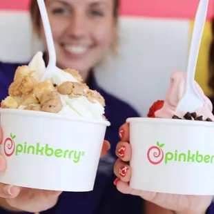 two women holding up two cups of ice cream