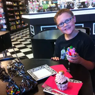 He's holding "I want candy" cupcake the other is chocolate salted Carmel