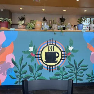 a coffee shop counter with a mural on the wall