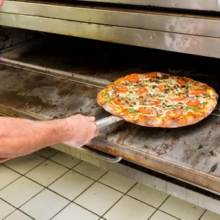 a man pulling a pizza out of the oven